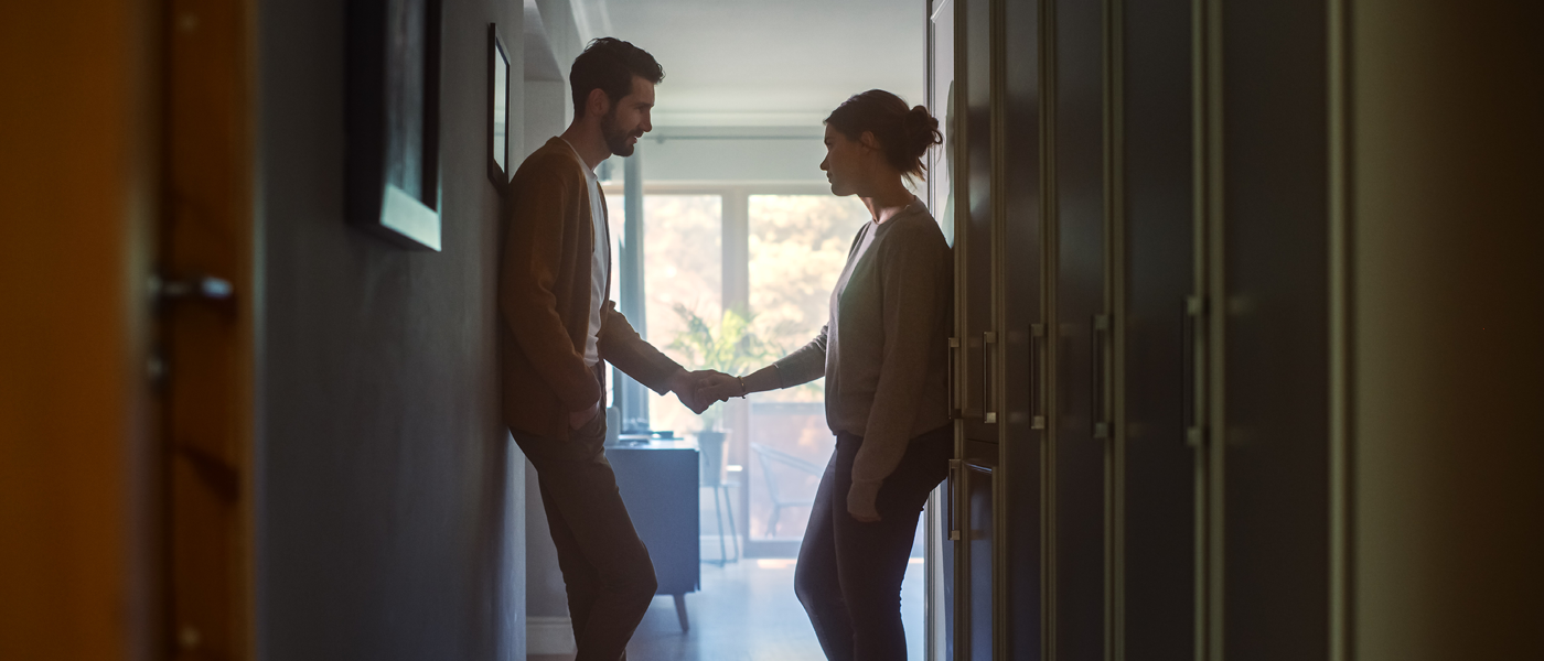 Two people holding hands in a hallway at home, conveying a moment of connection or reconciliation.