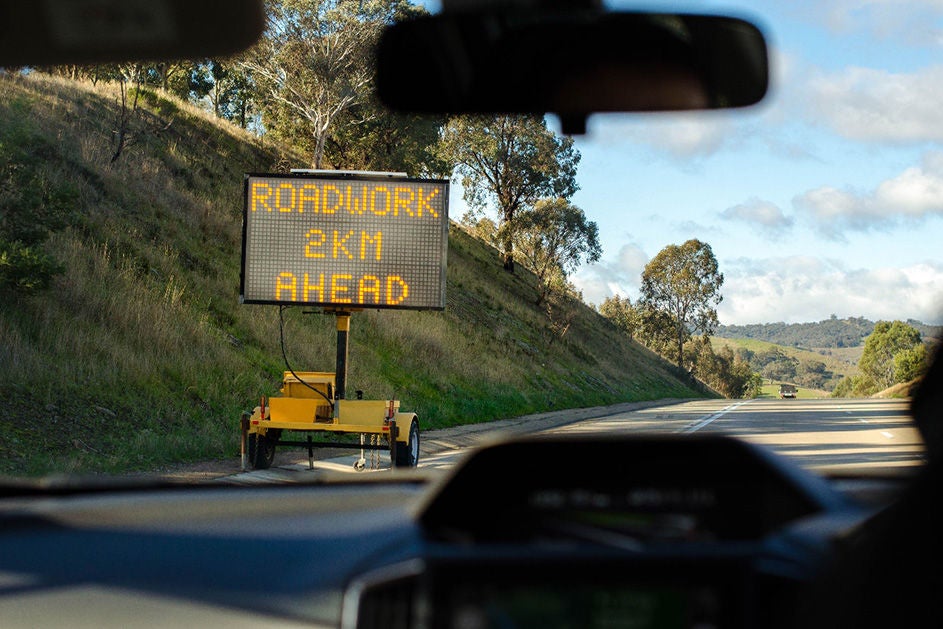A sign on the roadside marking there is roadwork 2 km ahead.