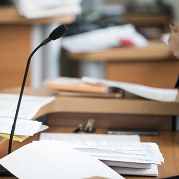 A lectern with many papers stacked on top and a microphone