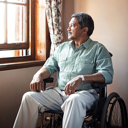 A man in a wheelchair in his home looking out the window