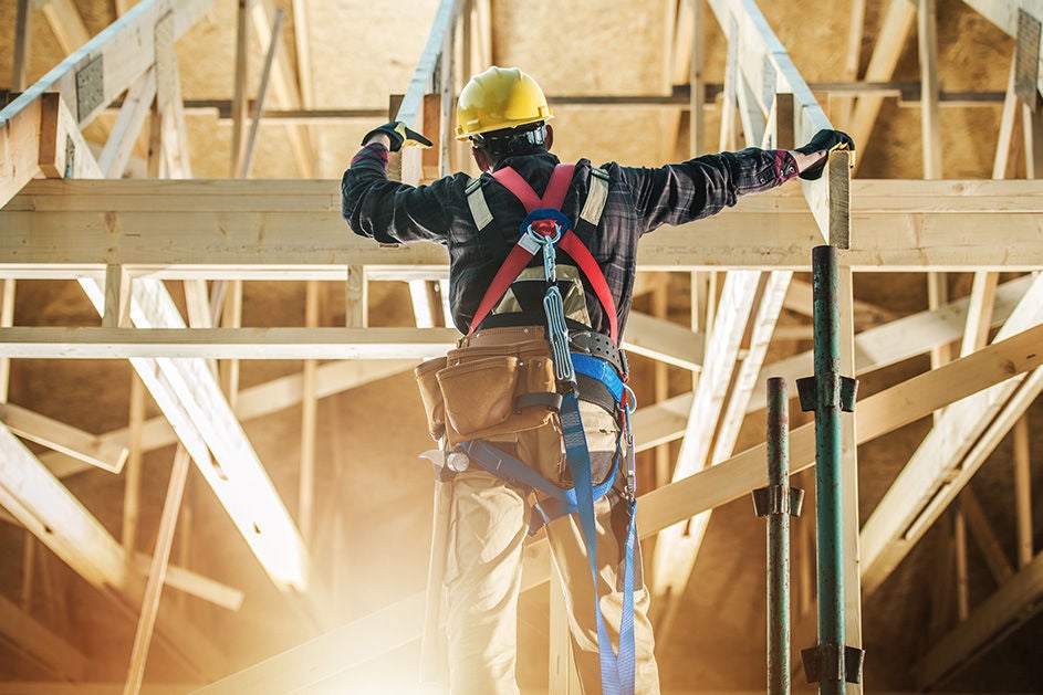 A man on a ladder performing maintenance work on a roof.