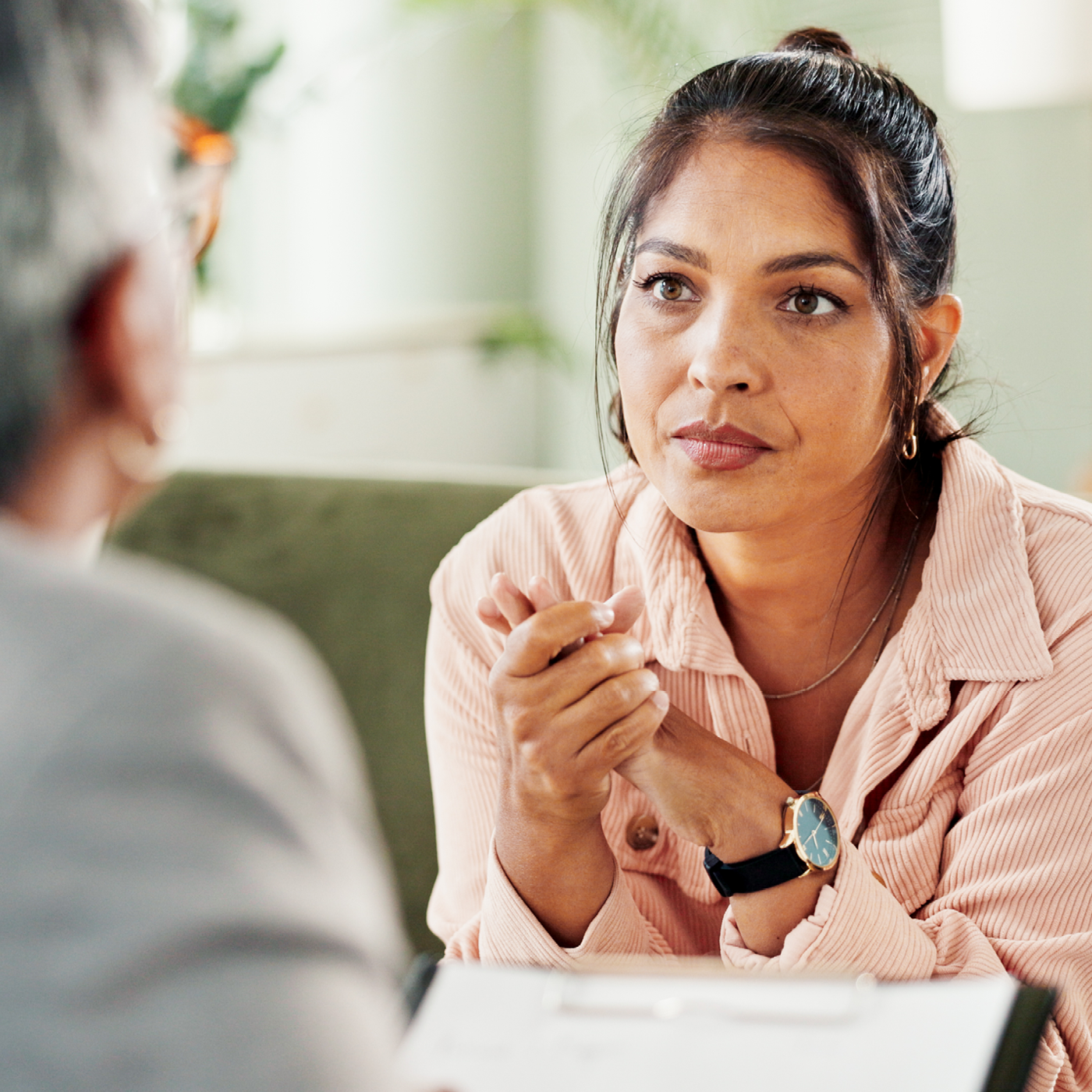 A woman in serious conversation with an older person while seated on a sofa, suggesting a sensitive or important family discussion.