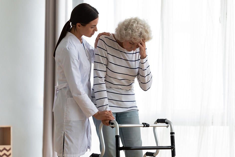 A caregiver helps an elderly woman with a walker, ensuring her safety and comfort while walking.