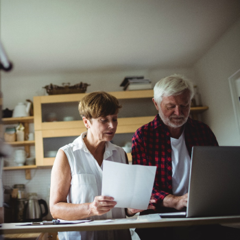 A man and a woman look concerned as they review a bill and laptop