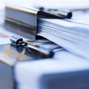 Stacks of paper held with black bulldog clips