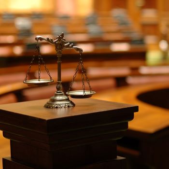 A small statue of the scales of justice atop a podium in a court room