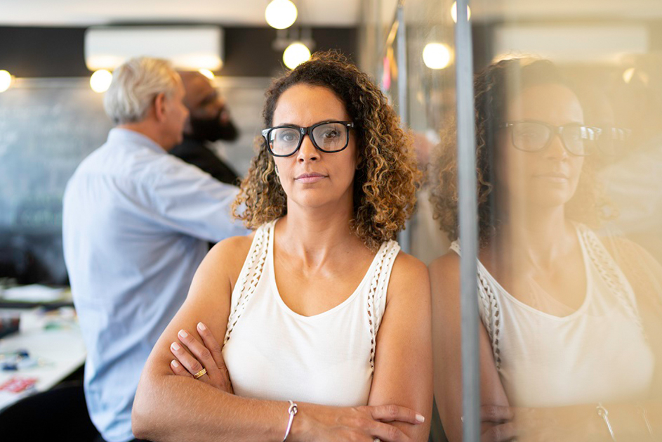 An employee standing in a meeting room with other people in the background