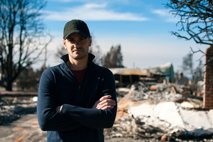 Man standing in front of burned house.