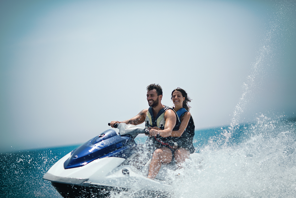 Two people safely riding a jet ski wearing life vests