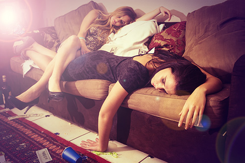 two women are asleep on a couch after what a party in their rental house