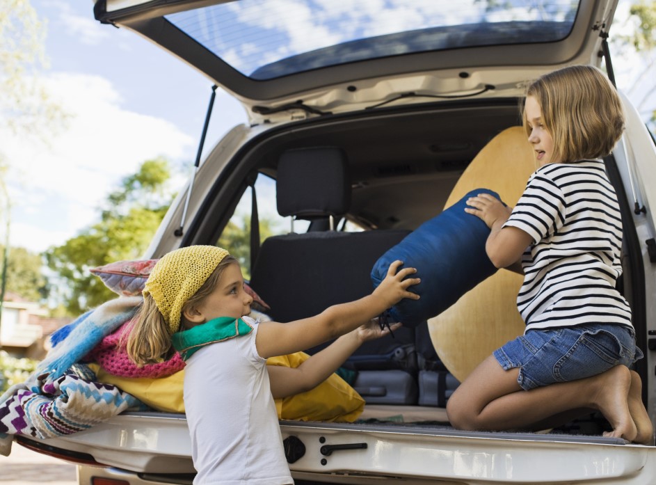 two girls pack a car for a road trip