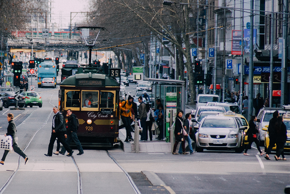 Traffic in Victorian city; trams, buses, cars and pedestrians all navigating a busy road