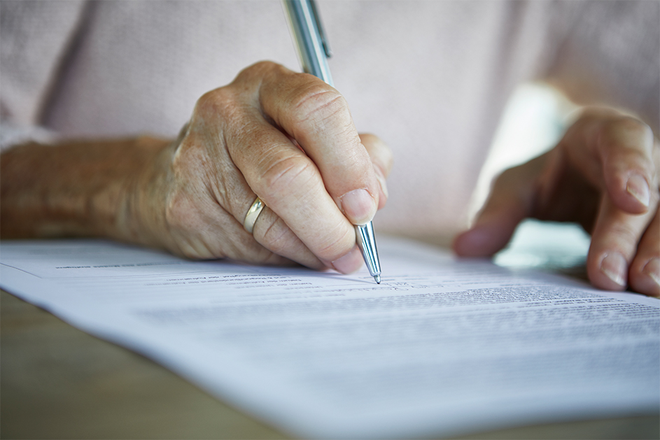 An elderly person signing a document