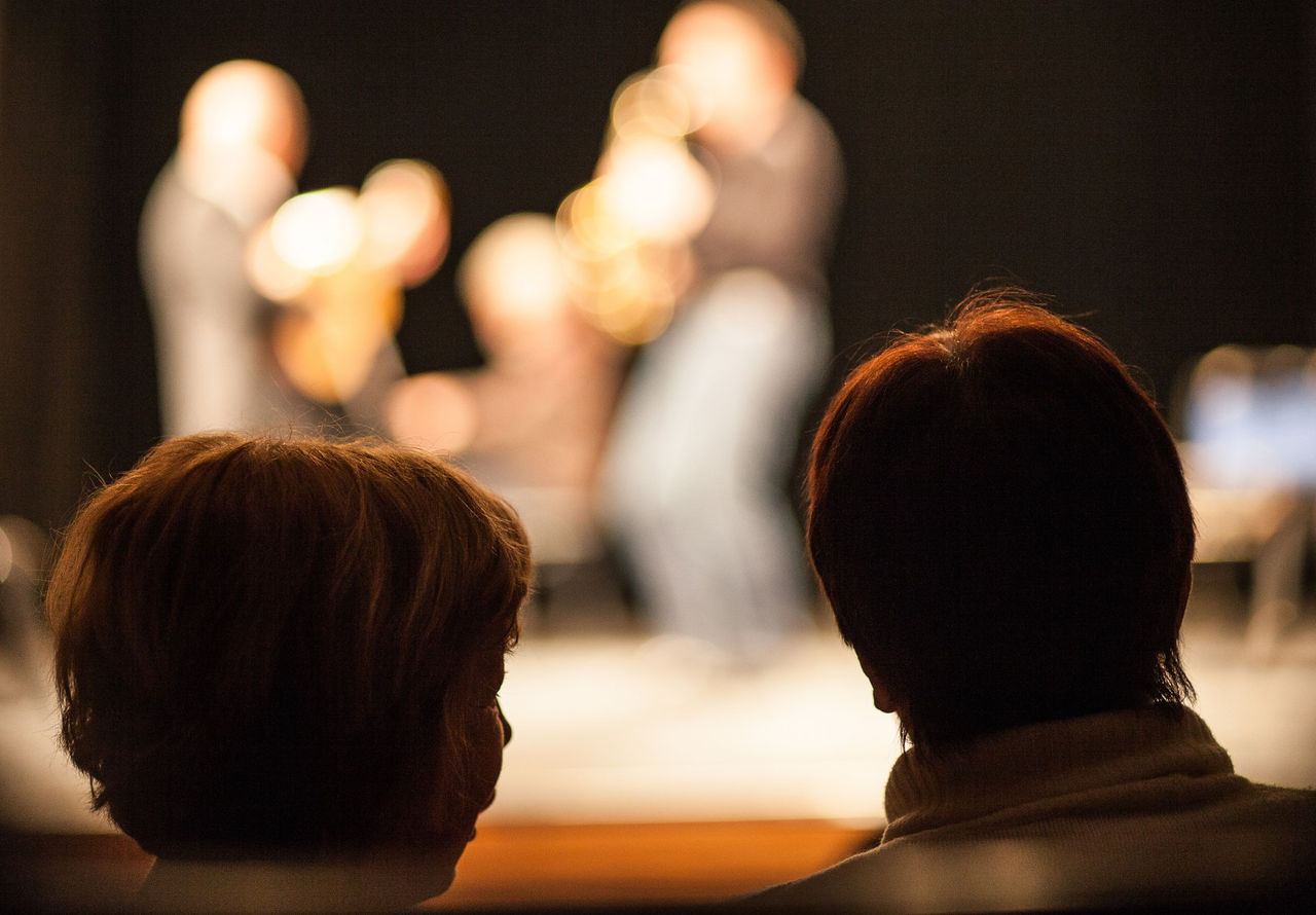 two people watch a stage show