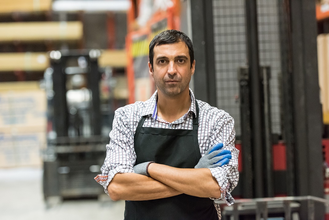 man posing at his place of work, a warehouse with fork lifts