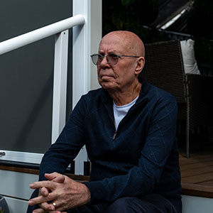 Maurice Blackburn client Phil sits on outdoor steps with his hands clasped, looking thoughtful.