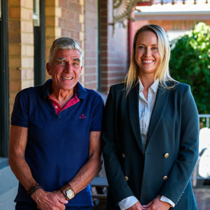 Maurice Blackburn client Brian and lawyer Nadia Lucas standing  side by side, both smiling.