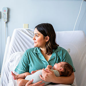 A woman cradles a newborn baby in her arms while resting in a hospital bed.