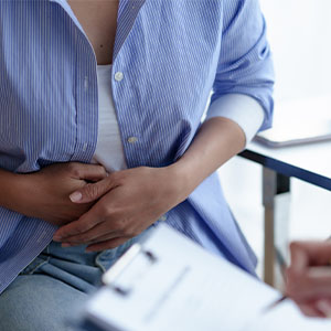 A woman sitting on a chair, resting her hands on her stomach.