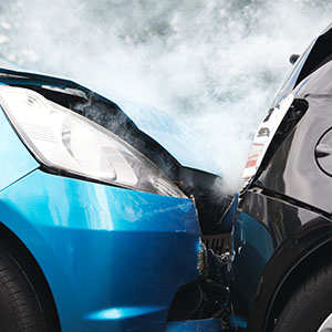 A damaged car shows visible dents and scratches after a collision with another vehicle.
