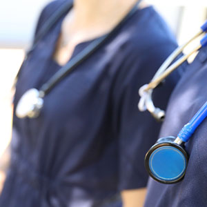 Close-up of healthcare professionals in navy scrubs, with stethoscopes visible.