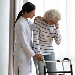 A caregiver helps an elderly woman with a walker, ensuring her safety and comfort while walking.