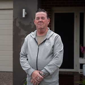 Maurice Blackburn client John standing in front of his house.