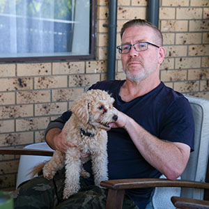 Maurice Blackburn client Roland sitting on a chair, with his dog on the laps.