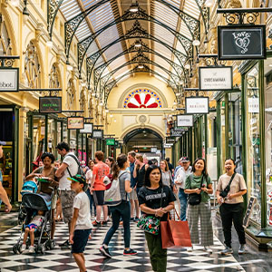 A group of people walking through a shopping mall featuring a distinctive checkered floor pattern.