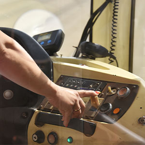 A person operating a control panel inside a vehicle, with one hand adjusting a lever and various buttons and switches visible..
