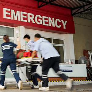 A doctor jotting down notes on a notepad, surrounded by medical equipment in a clinical setting.