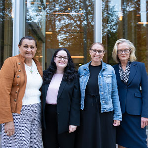 Maurice Blackburn lawyer Naomi standing side by side with clients in front of a glass window.